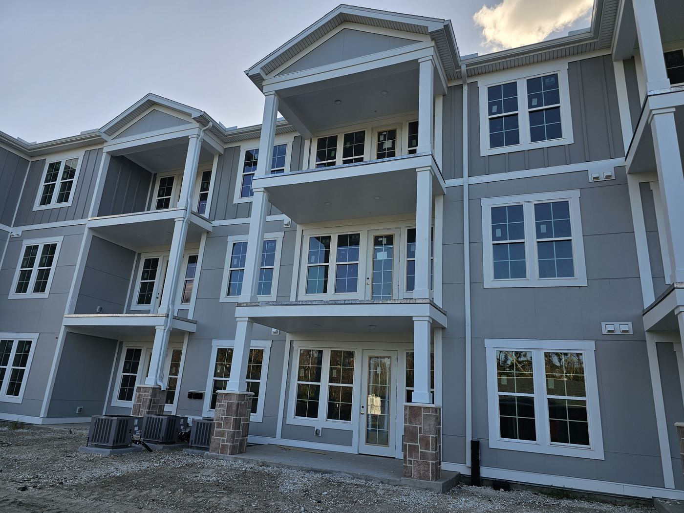 Three-story building with gray siding and white trim