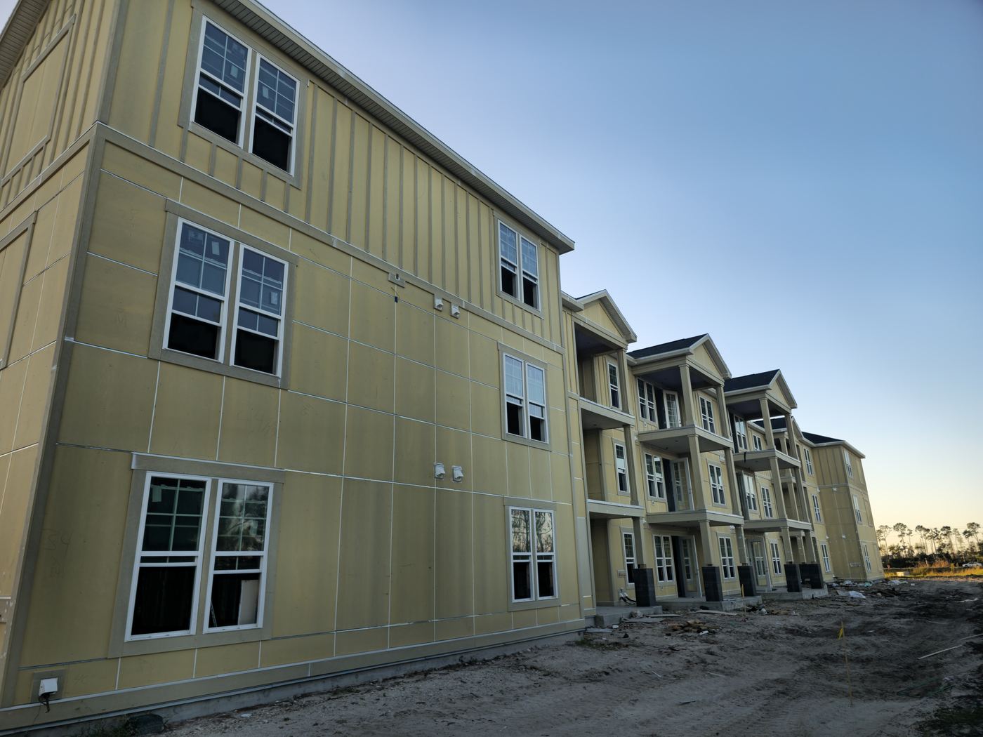 Multifamily building with primed siding at sunset